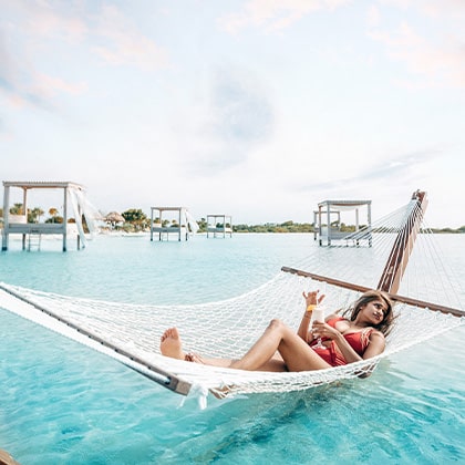 Woman in overwater hammock at the Beach Club at Mahogany Bay Resort & Beach Club
